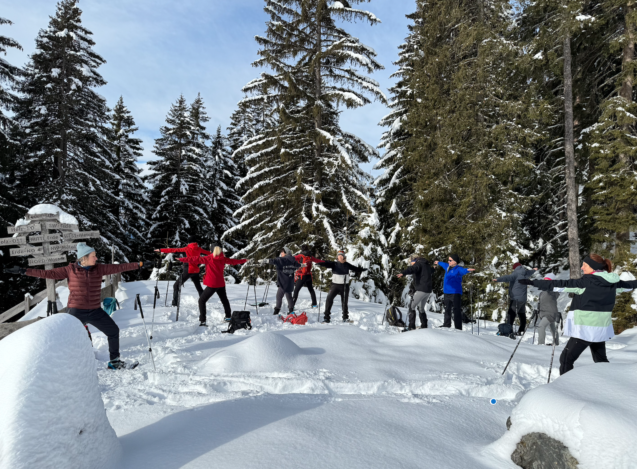 Yoga in Tirol auf Schneschuhen – Teilnehmer praktizieren Yoga auf einer verschneiten Bergwiese mit Blick auf die Alpen.